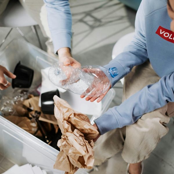 Volunteers in blue shirts sorting recyclable materials like paper and plastic.